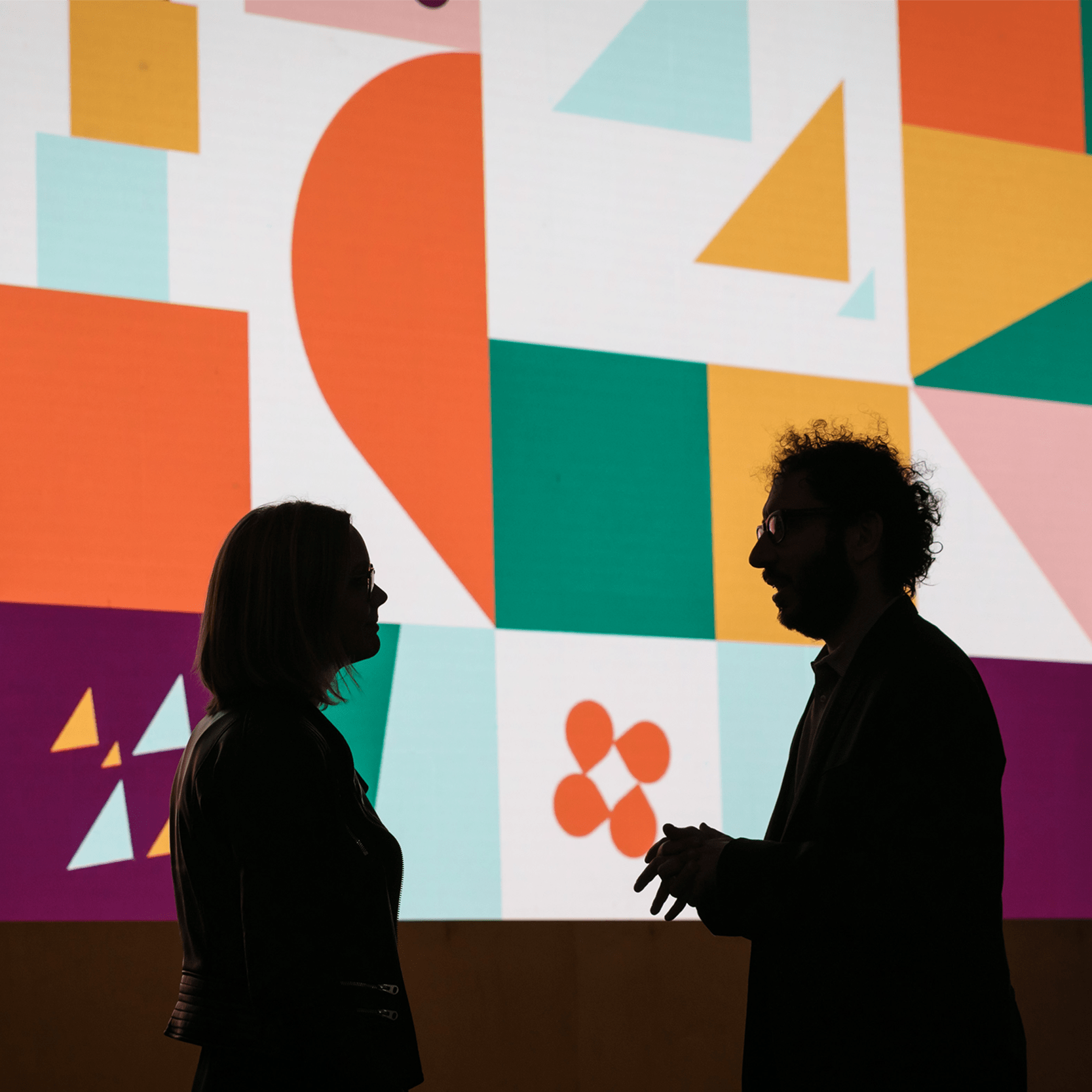 two attendees at Slack Frontiers talking in front of a large illustration